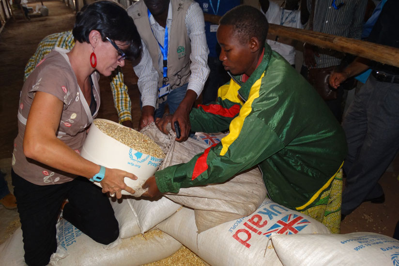 Laure Beaufils, the head of DFID Rwanda helps distribute maize.