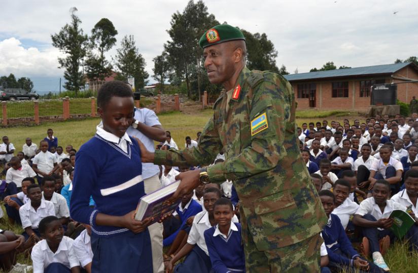 Maj Gen Kazura hands book to a student during the donation of books to four schools in Musanze. (Jean d'Amour Mbonyinshuti)