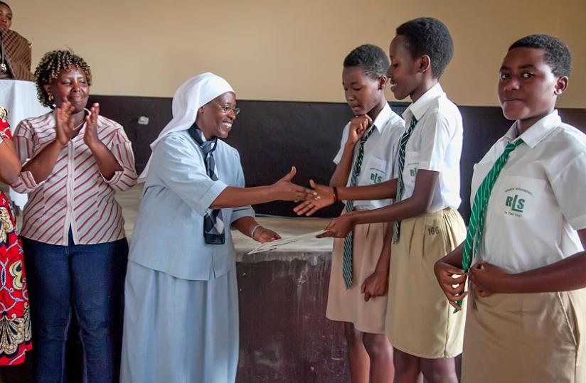 Sister Marie Eugenie Kairaba, the headmistress of FAWE, gives certificates to the students who participated in the debate.  (Hudson Kuteesa)