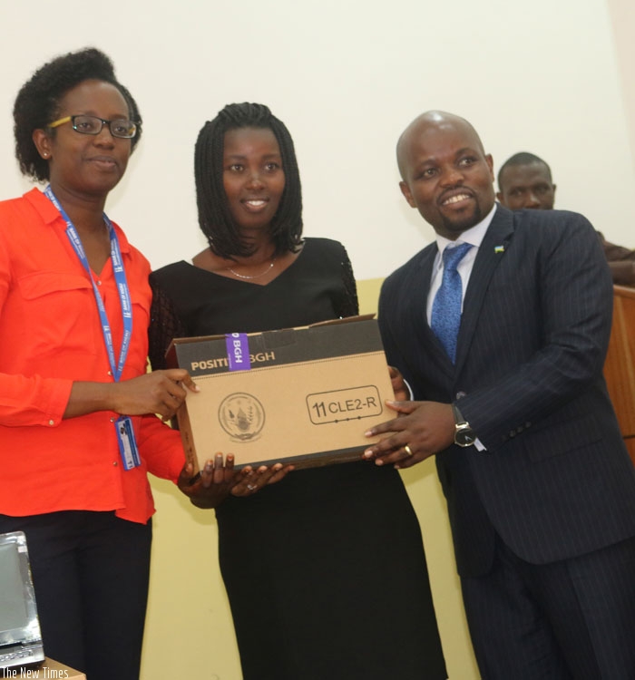 BK' s Diane Karusisi (L), Minister Nsengimana (R) hand over a laptop to one of the students. (Steven Muvunyi)