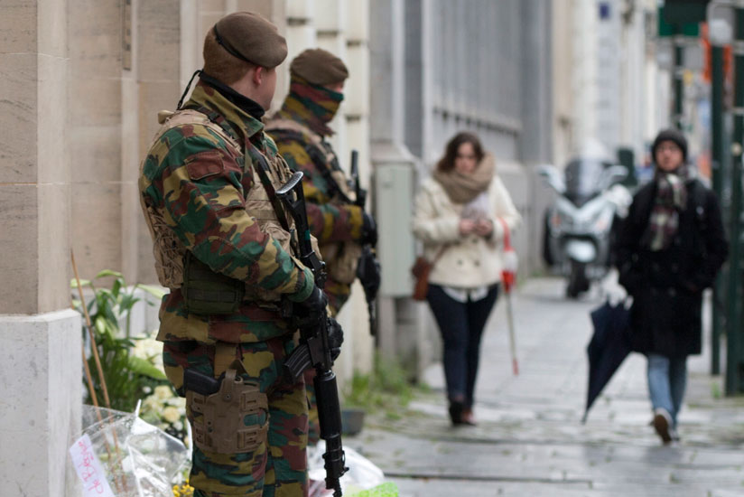 Belgian Army soldiers patrol next to flowers left in remembrance of terror attack victims in Brussels recently. (Internet photo)