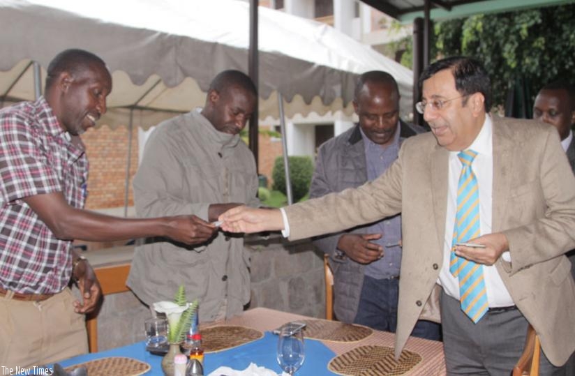 Anand (right) exchange business cards with Musanze clients and shareholders on Friday. (Hudson Kuteesa)