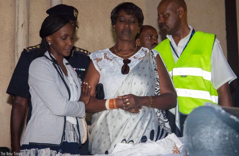 Bihozagara's widow, Jeanne Bihozagara and their daughter Bonita Isaro look at the casket containing the remains of the former Cabinet minister and diplomat, upon its arrival at  Ki....