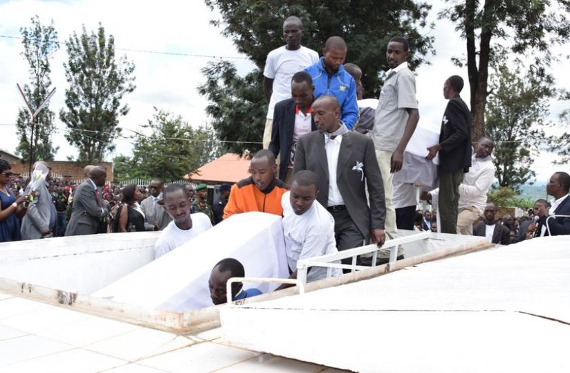 Bodies being lowered into the grave at Kiziguro memorial site on Monday. (Kelly Rwamapera)