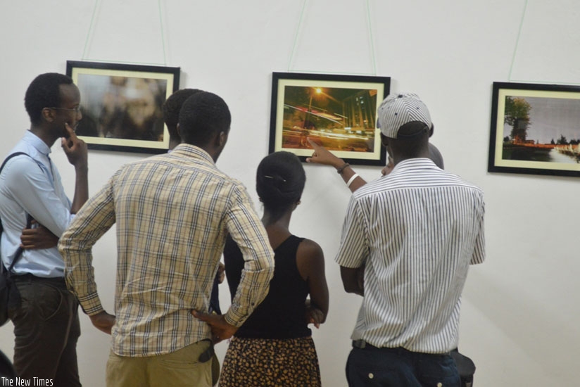 A photographer explains to guests about his work on display. (Julius Bizimungu)