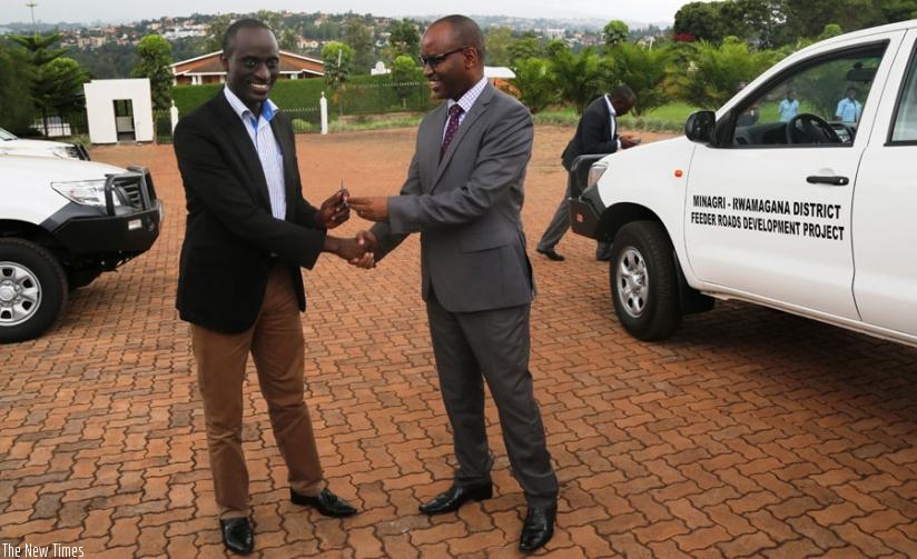 Musabyimana (right) hands over one of the car keys to  Kakooza, the Rwamagana District executive secretary at the agriculture ministry head offices. (Peterson Tumwebaze)