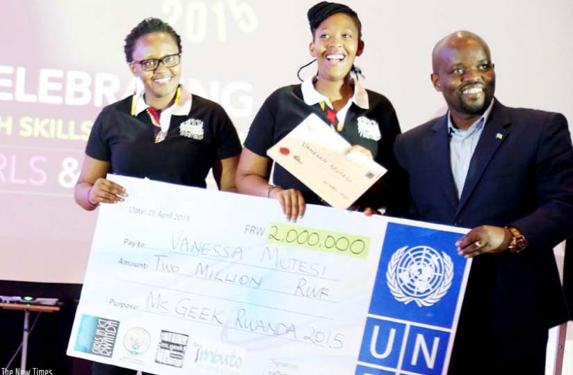 The Minister for Youth and ICT, Philbert Nsengimana hands over a dummy cheque to a past Ms. Geek winner. (Net photo)