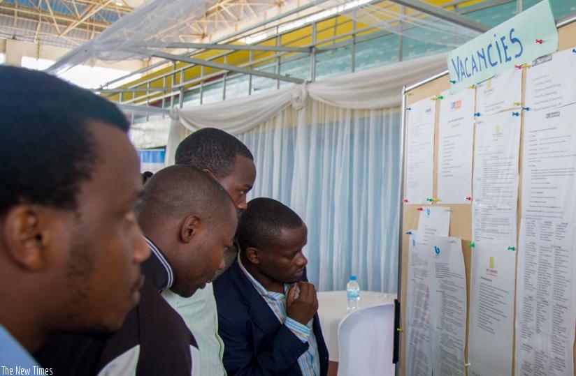 Jobseekers look for job opportunities on a notice board displayed at the third Kigali Employment Fair at Petit Stade in Remera, Kigali yesterday. (Timothy Kisambira)
