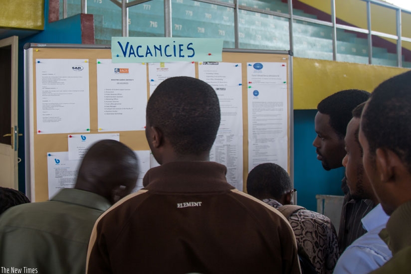 Job seekers look for job opportunities on a notice board displayed at the third Kigali Employment Fair at Petit Stade in Remera earlier this week. (Timothy Kisambira)