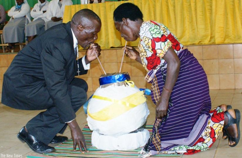 A Genocide survivor (R) shares a traditional brew with her former termentor, Aphrodis Kanani, from the same calabash after forgiving him. (Frederic Byumvuhore)