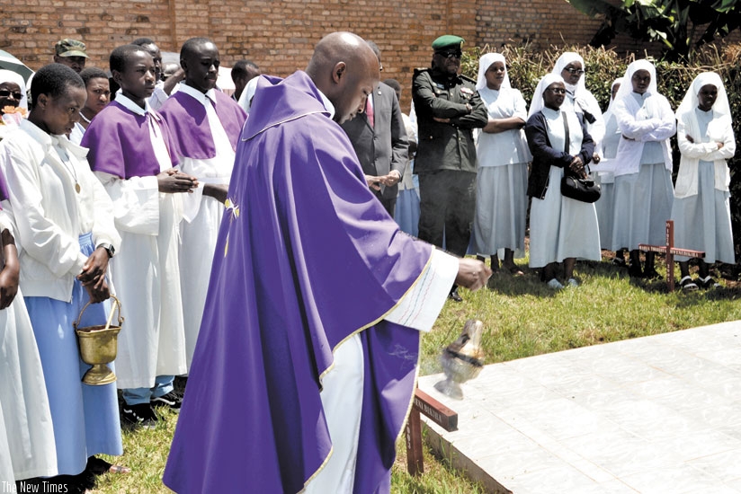 Fr Jean Claude Ndatimana of the Carmelite Fathers sprinkles incense on the monument erected at Save Parish in remembrance of the nuns killed in the Genocide. (E. Ntirenganya)