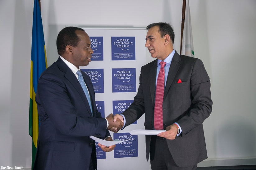 Gatare and Malhotra exchange documents after the signing in Kigali yesterday. (Courtesy)