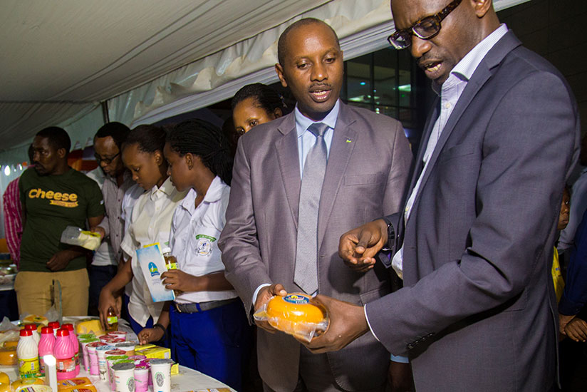 NAEB Chief Executive George William Kayonga (L) and Alex Ruzibukira, the director of investments and industries at the Ministry of Trade and Industry,  check out cheese on exhibition on Thursday. Cheese makers have been urged on consistency in producing quality and well branded products that comply with international standards as a sure way of expanding their market. (Faustin Niyigena)