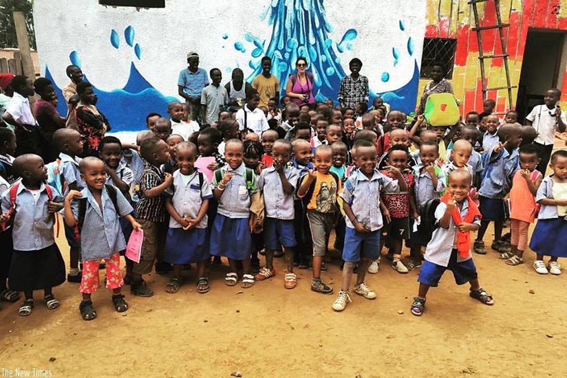 School pupils and the artists pose for a photo in front of one of the painted walls. (Moses Opobo)