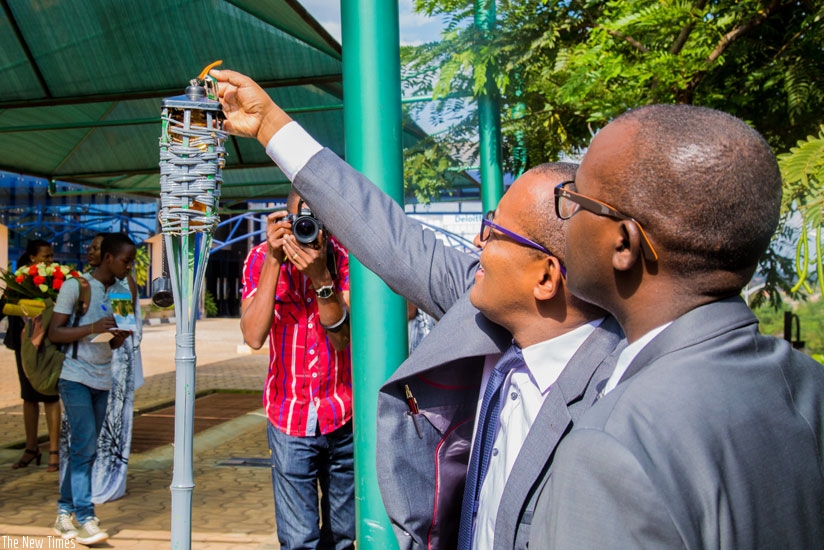 CNLG legal advisor Dr Diogene Bideri lights the Flame of Hope at RSSB Genocide monument as the Director General Jonathan Gatera looks on. (Faustin Niyigena)