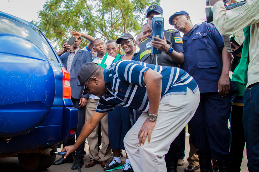 The Minister for Natural Resources, Dr Vincent Biruta, tests levels of carbon emissions from a car as police officers verify if the results match with the environmental standards. (Faustin Niyigena)