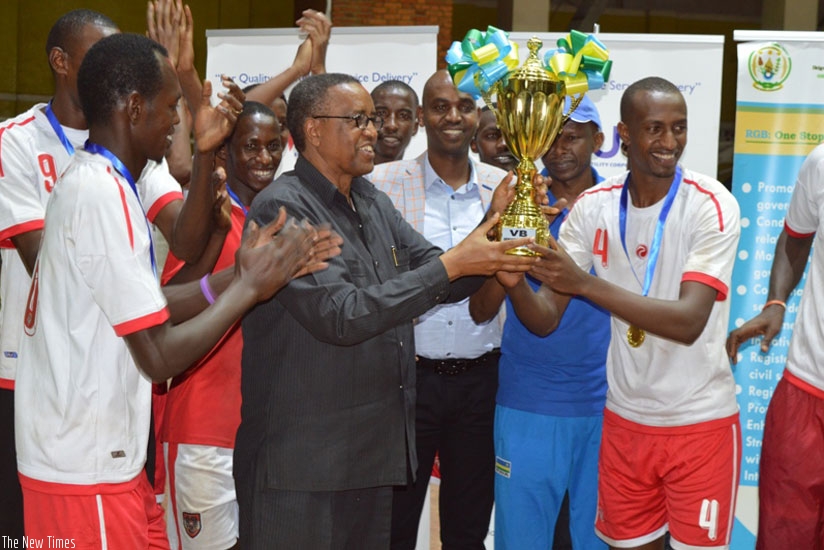 INATEK Vice Chancellor Prof. Silas Lwakabamba (C) lifts the Genocide Memorial Volleyball tournament trophy as players cheer on. (Geoffrey Asiimwe)