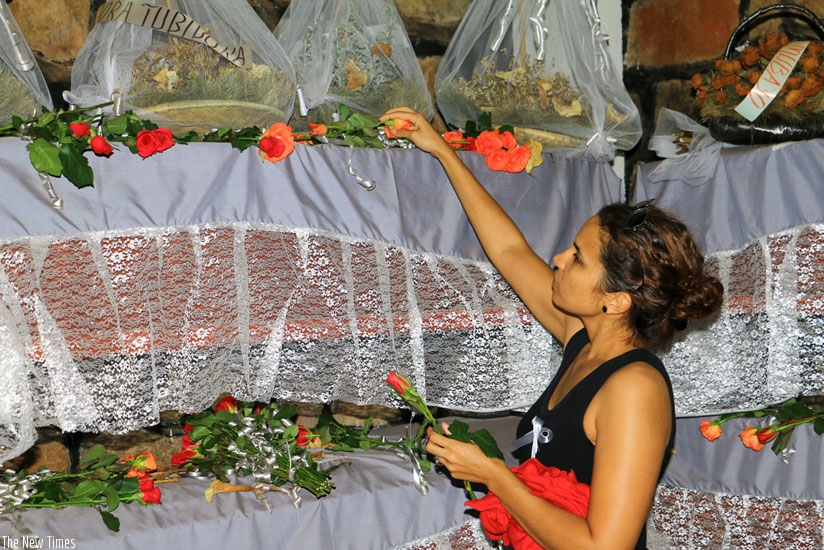 A survivor lays a flower at the site in tribute to relatives killed in the Genocide. (Frederic Byumvuhore)
