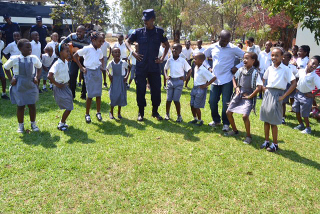 A police officer plays with pupils during one of the awareness campaigns on child protection in schools. (Courtesy)