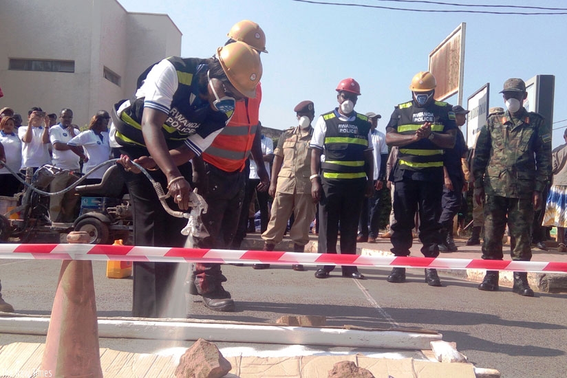 City of Kigali mayor Monique Mukaruliza paints a zebra crossing at the launch of the annual Police Week as IGP Emmanuel K. Gasana (2nd R) and other officials look on. (Timothy Kisambira)