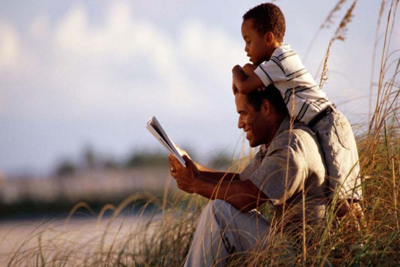 A proud father reads a story to his son. (Net photo)