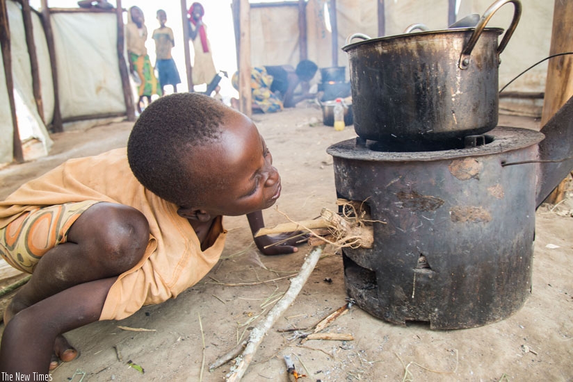 A Burudian child prepares a meal at Mahama refugee camp. Environmentalists are warning about the dire effects of cutting trees for firewood. (Timothy Kisambira)