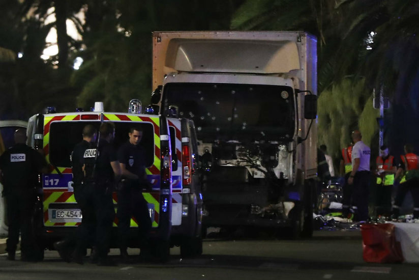 Police officers and rescue workers stand near a truck that plowed into a crowd leaving a fireworks display in the French Riviera town of Nice. /Getty Images