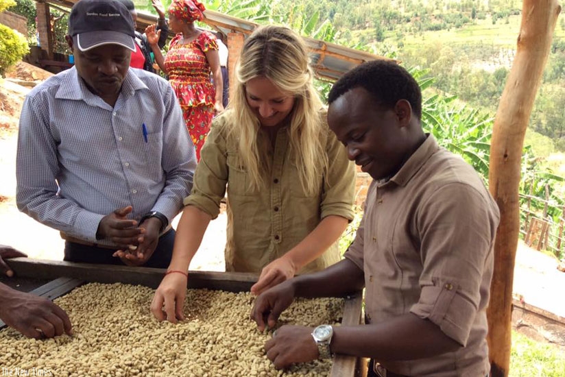 Murindababisha (right) is joined by his customers to spread coffee beans on drying rack at his factory in Kayonza. (Francis Byaruhanga.)