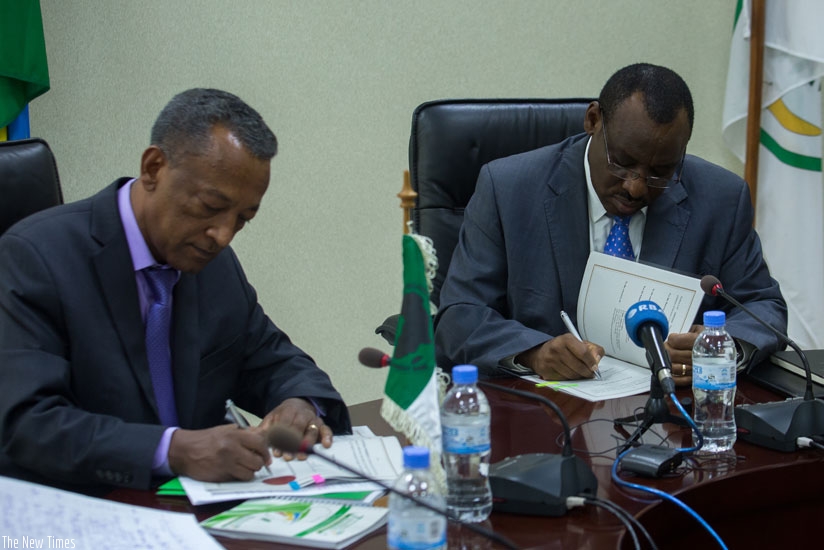 AfDB resident representative Negatu Makonnen (L) exchanges documents with Minister Gatete in Kigali yesterday. (Timothy Kisambira)