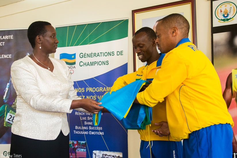 Minister Julienne Uwacu hands over the national flag to the Paralympic team captain Muvunyi (C) and head of delegation, Eric Karasira. (Faustin. Niyigena.)