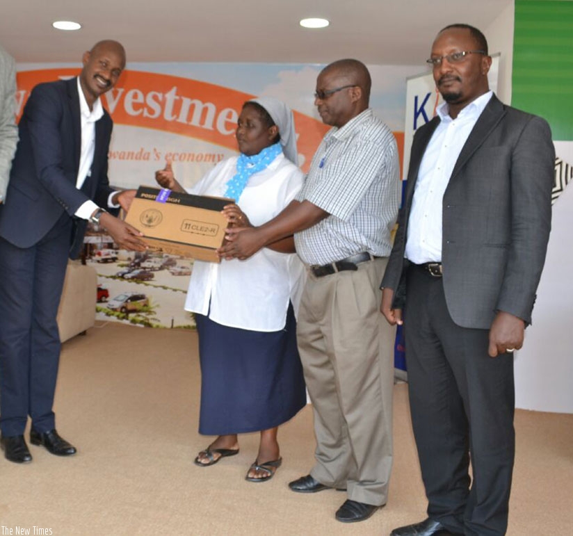 Karasira (left) hands over a laptop to Sister Nayituriki and Edouard Uhagaze, the Lycee Notre Dame de Citeaux deputy head teacher in charge of studies, while Victor Nkindi (right) ....