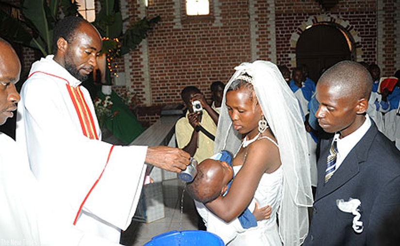 A priest baptizes a baby. A group of young Pan-Africanists is pushing for a campaign to promote exclusively Rwandan names for newborns, with some activists seeking a change of thei....