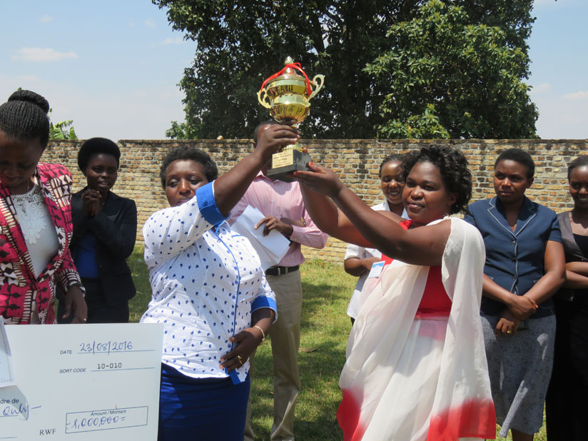 Mayor Uwamariya (L) hands over a trophy to the best performing cooperative, Tuzamurane, during the closing ceremony of the 10-day training in Muhanga District on Thursday. / John Mbaraga.