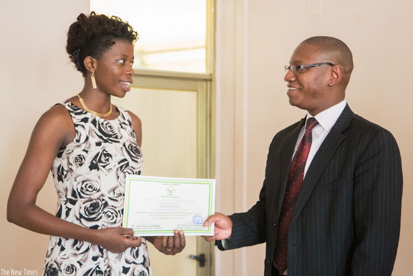 Minister Ndimubanzi (R) certifies one of the new doctors deployed to hospitals yesterday. / Faustin Niyigena. 