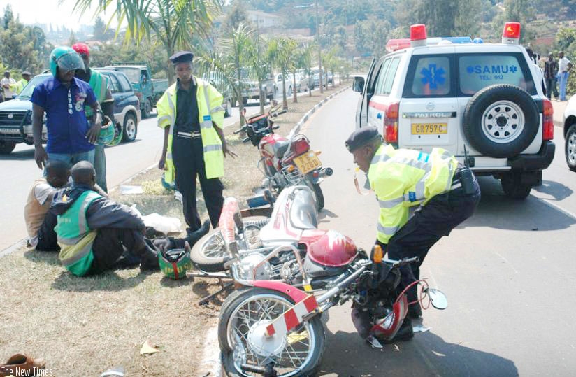 A Police officer removes a motorcycle from the scene of an accident in Kimicanga.
