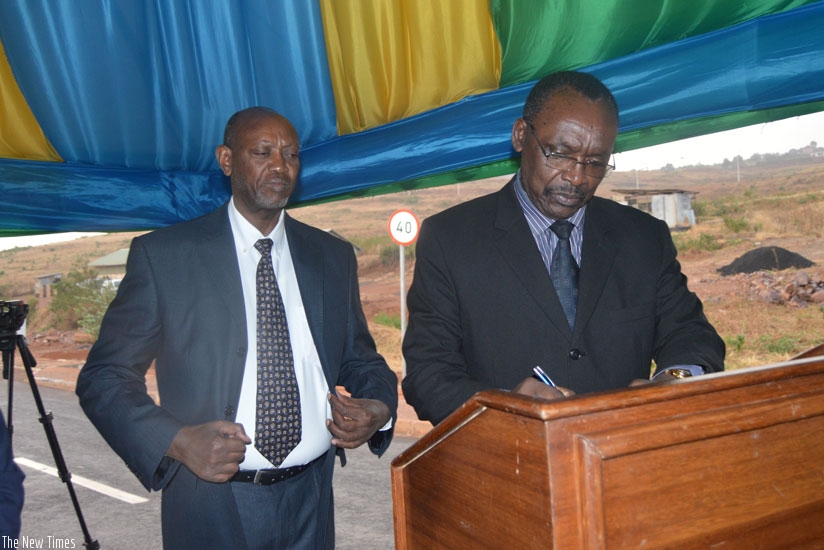 Minister Kanimba signs while Albert Nsengiyumva of Albert Supplies looks on. 