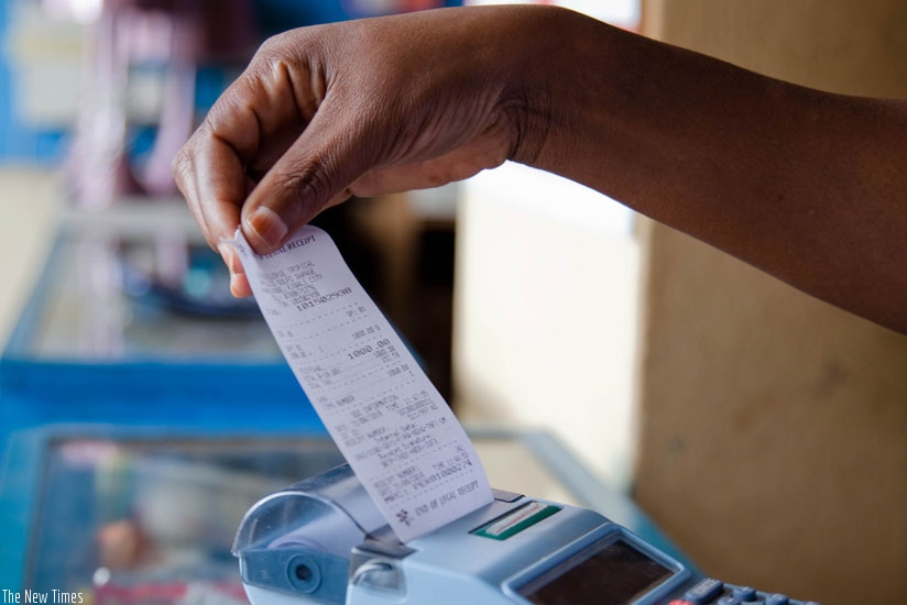 A trader pulls a receipt out of a billing machine at Mateus in Kigali. (File)
