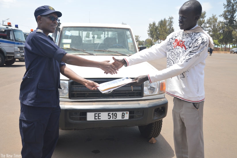 Tony Kulamba, the Commissioner for Interpol and Cooperation at Rwanda National Police, hands over the recovered vehicle to Jacob Garang Deng, a South Sudanese national, at the Forc....