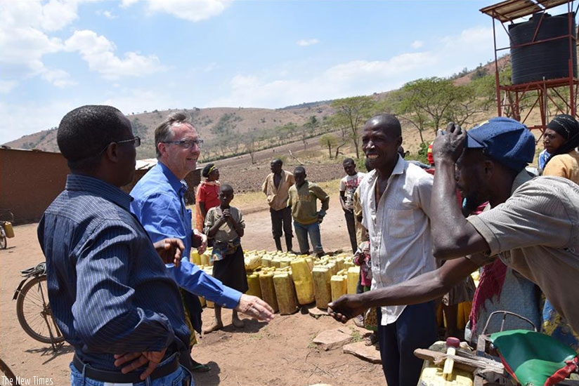 Water for Growth Team Leader, Ebel Smidt and the Head of the Integrated Water Resource Management Department, Vincent de Paul Kabalisa discuss with residents who came to fetch at t....