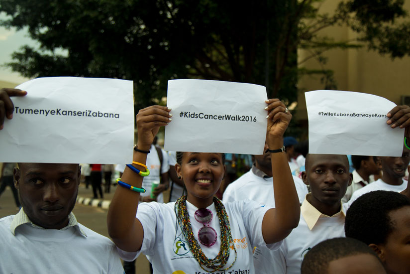 Youths raise placards during the kids cancer walk awareness campaign at car-free zone in Kigali. / Timothy Kisambira