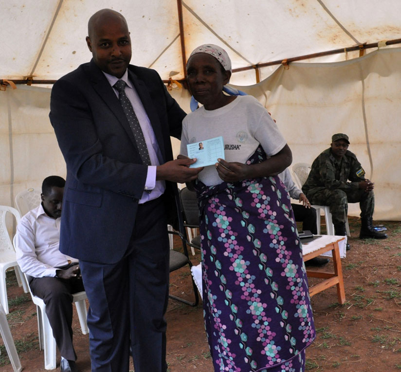 Jean-Marie Nkurayija, representative of Rwandan community in Ethiopia, handing over Mutuelle de Sante card to an elderly woman in Ntarama./ Courtesy