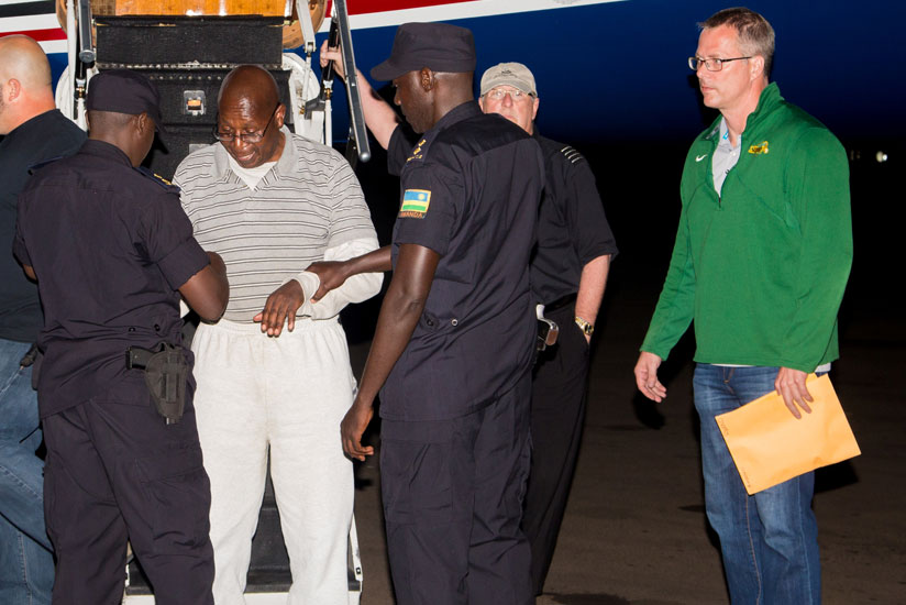 Genocide suspect Dr Leopold Munyakazi gets handcuffed after landing at Kigali International Airport yesterday. / Photographs: by Faustin Niyigena