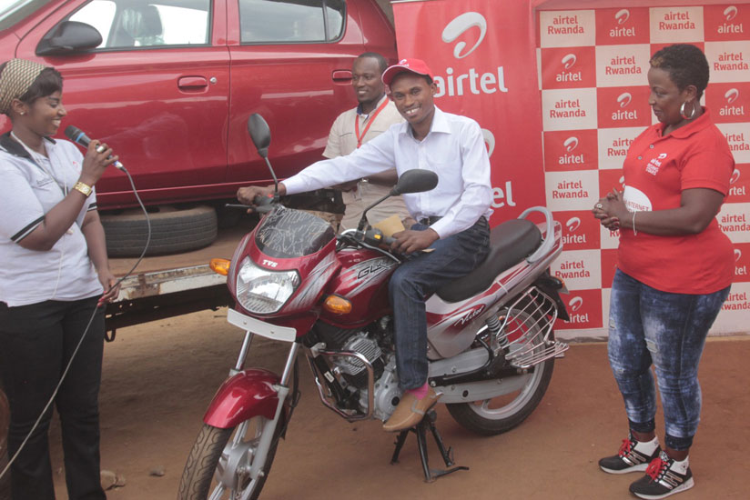 Mbarushimana tries out the motorcycle as Airtel officials cheer. / Francis Byaruhanga. 