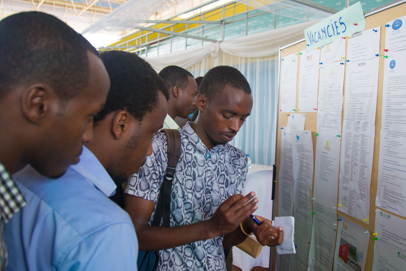 Job seekers look for job opportunities on a notice at Kigali Employment Fair at Petit Stade in Remera earlier this year. / File. 