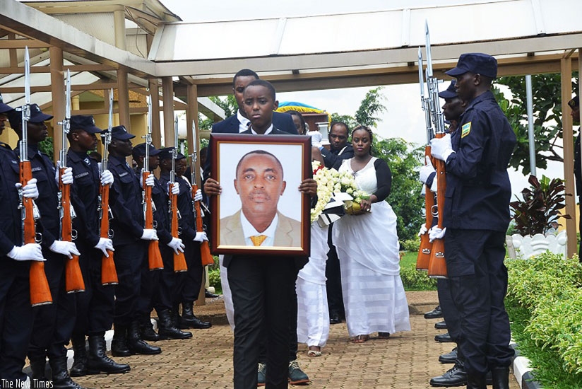 One of Mucyo's children holds a portrait of his father as the body arrived at parliament yesterday where the deceased was commended for exceptional service. / Sam Ngendahimana.