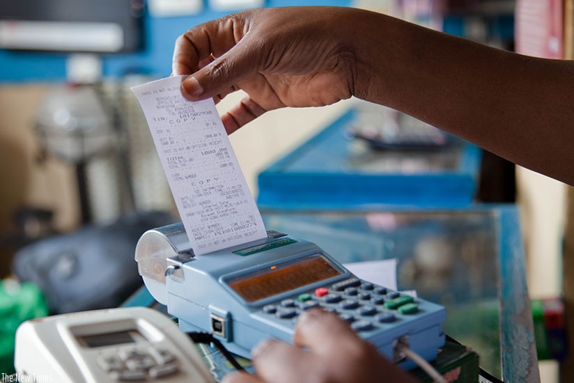 A trader pulls a receipt out of an electronic billing machine (EBM) in Kigali. A new law that seeks to make the use of EBMs mandatory for every business in the country to end unfai....