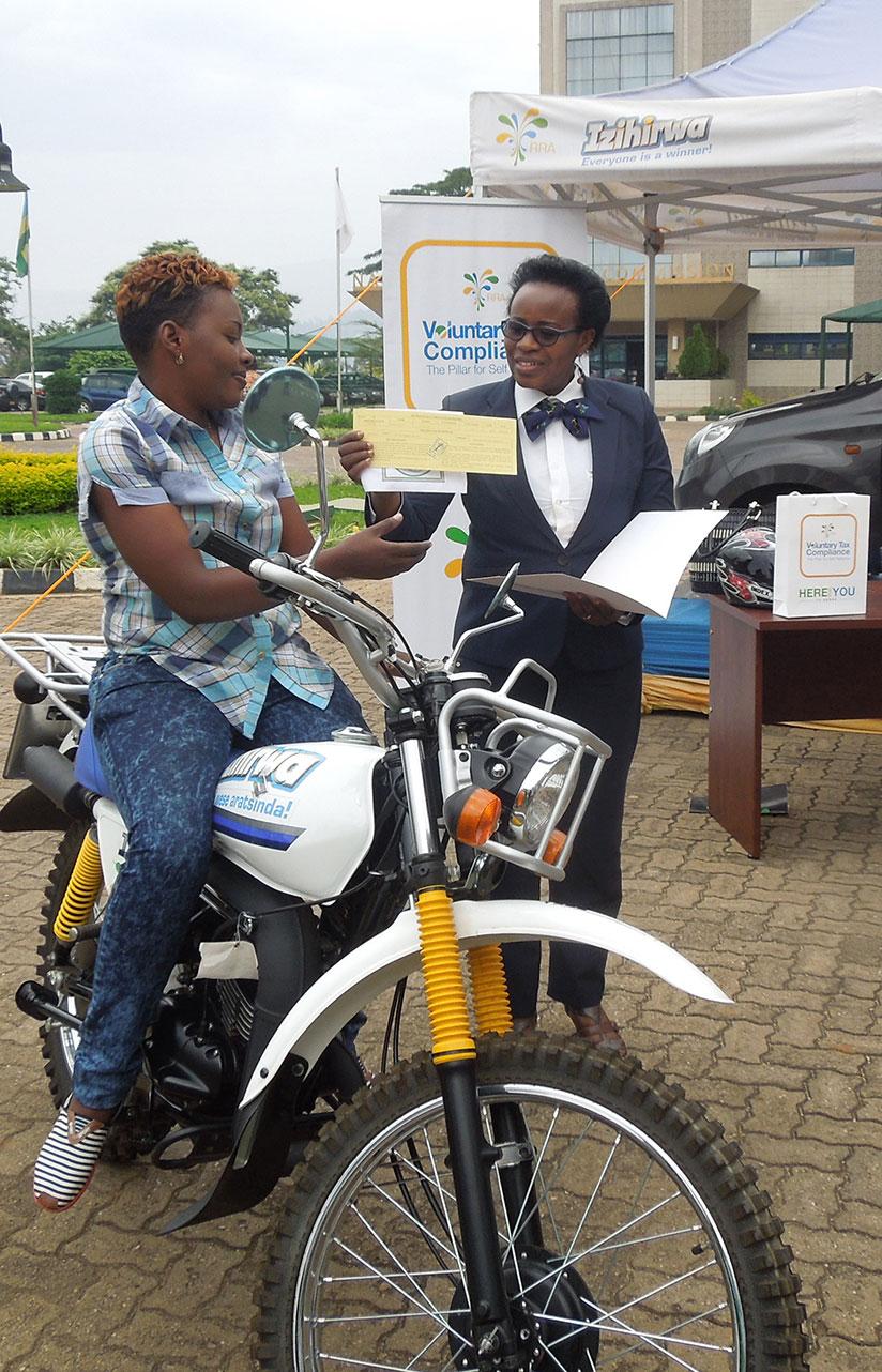 Niyigena receives the motorcycle documents from Drocella Mukashyaka, the RRA deputy commissioner for taxpayer services. / Appolonia Uwanziga