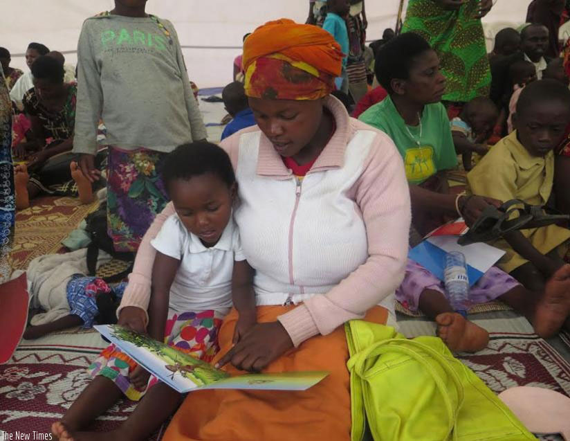 A parent helps her child to practice how to read. / Francis Byaruhanga 