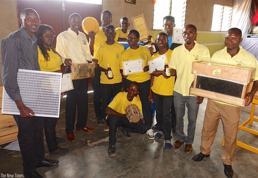 K+H staff pose for a group photo with students carrying beehives. / Sharon Kantengwa.