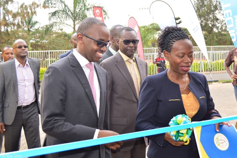 Nsanzabaganwa (R), flanked by Eric Rwigamba, the Ministry of Finance director general for financial sector development, cuts the tape to open the electronic and digital financial s....